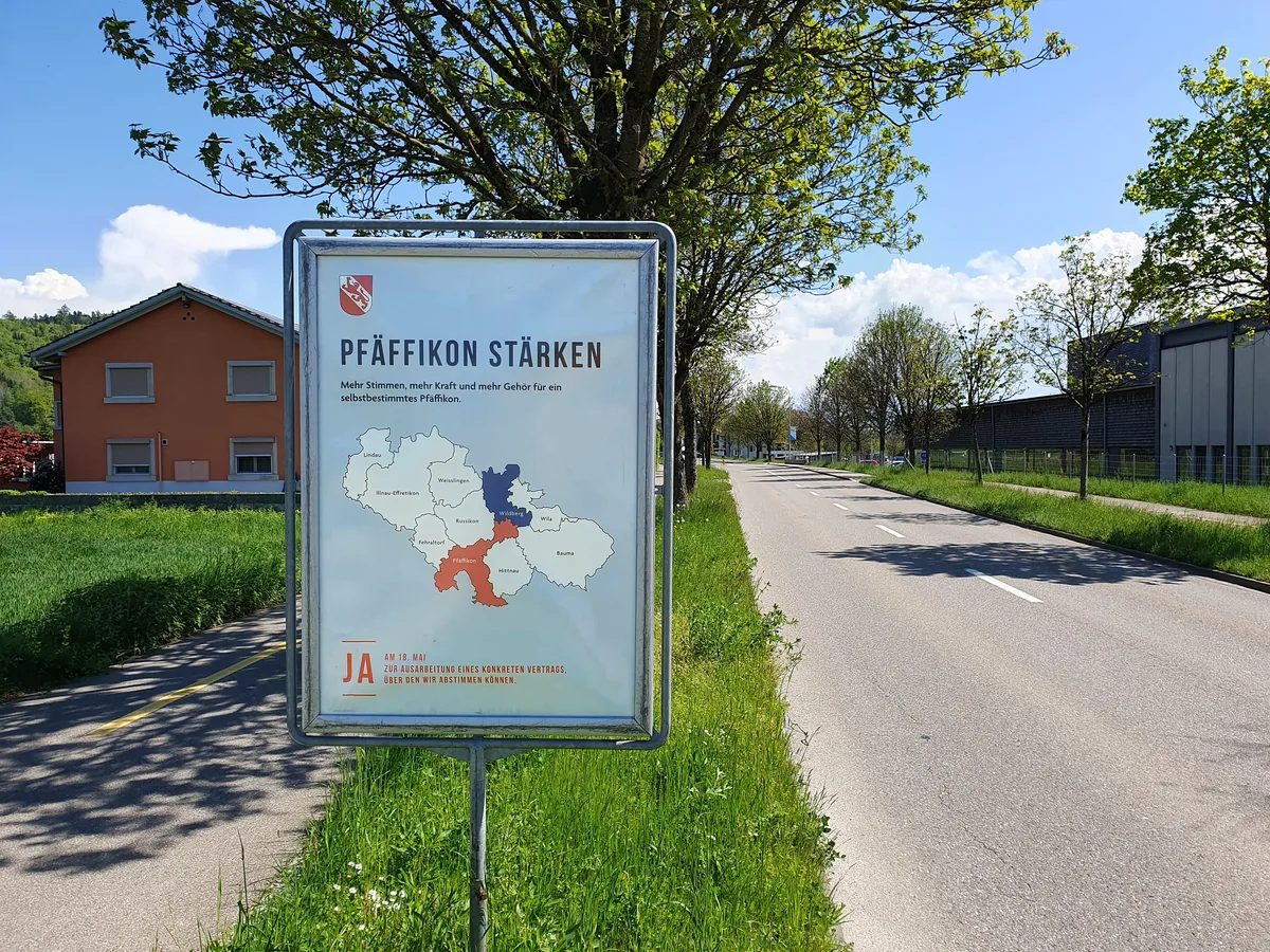 Man sieht einen Plakatständer mit einem Plakat, das für die Fusion von Pfäffikon und Wildberg wirbt.